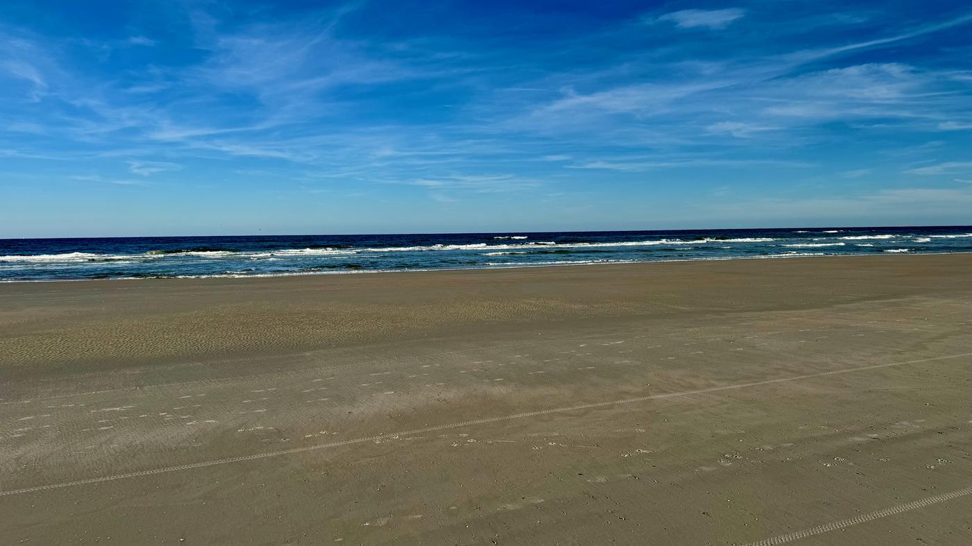 Wide empty beach under a deep blue sky